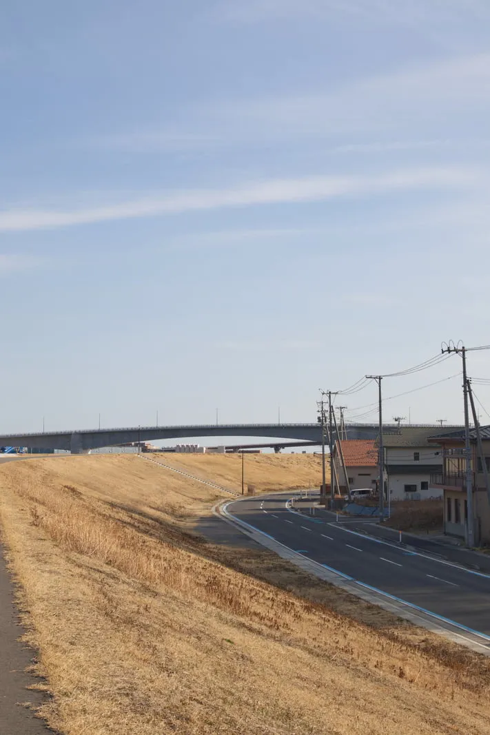 旧北上川の土手に沿ってカーブを描く道路と、石巻かわみなと大橋の写真