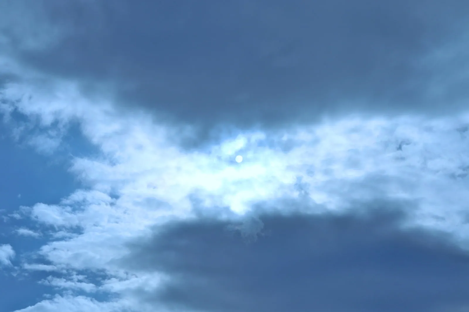 雲に覆われても強く光る太陽の写真